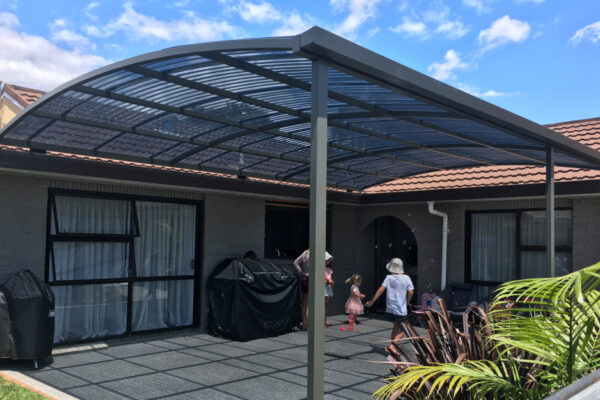 A curved pergola covering a large concrete patio area.