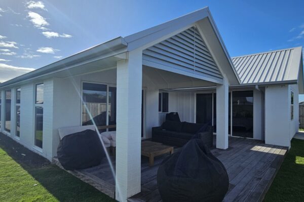 Side view of a pergola with metal roofing and decorative louvre in front.