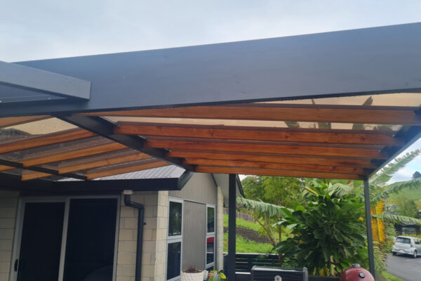 A gabled-pergola constructed of wood and opaque material.