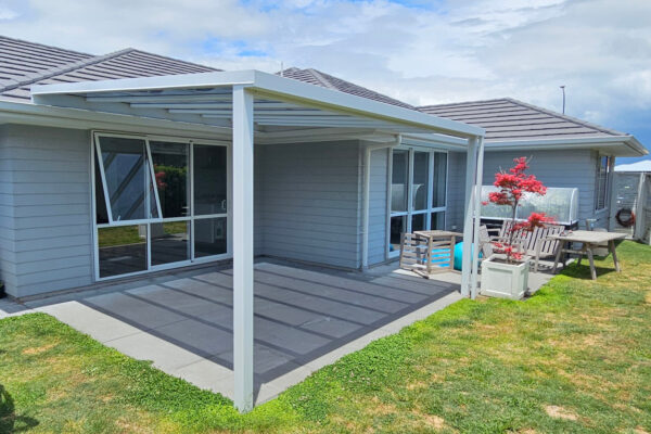 Metal pergola covering a small patio in a backyard.