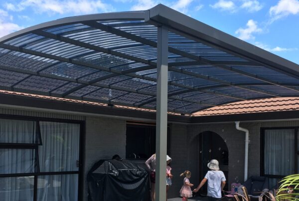 A curved pergola covering a large concrete patio area.