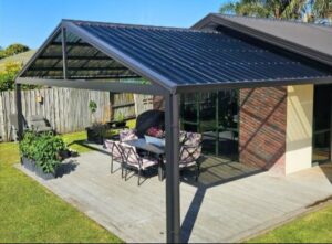 A gable pergola covers an outdoor patio with seating area.