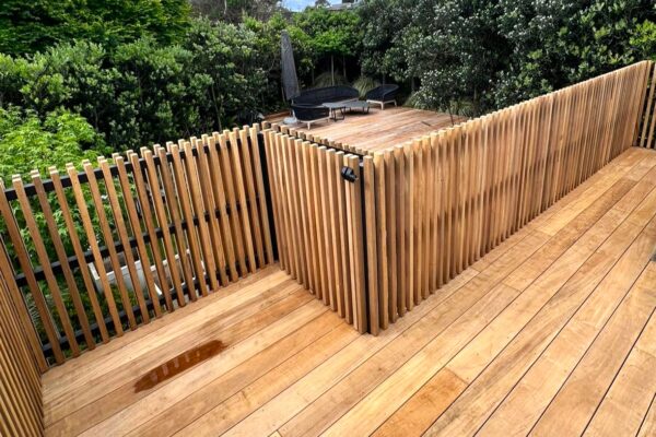 A wood slat gate and fencing surround a deck.